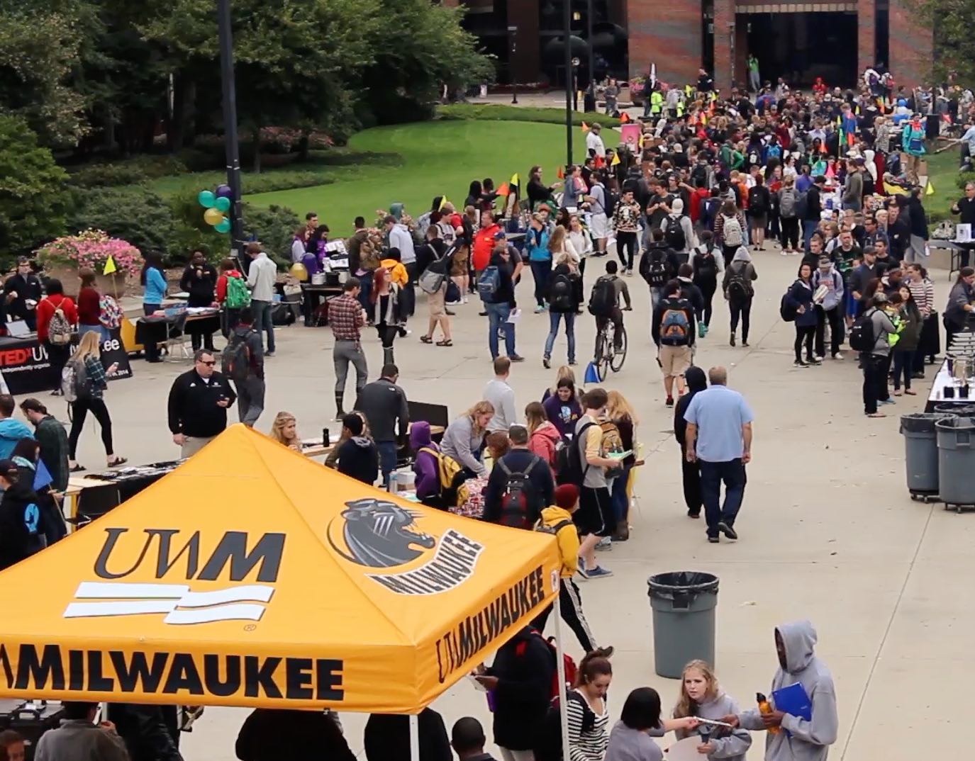 A busy college fair with a tent reading UWM in the foreground